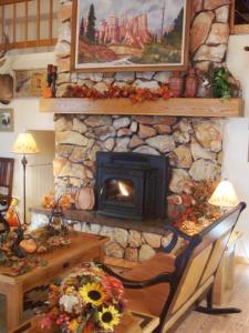 a stone fireplace in a living room with a wooden table and a table sidx sidx at Bryce Canyon Pines in Bryce Canyon
