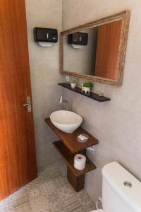 Un baño con lavabo, espejo e inodoro. en LAS ROZAS Parador, en Praia do Rosa