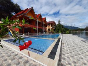 a resort with a swimming pool next to a building at Mas Cottages in Tuktuk Siadong