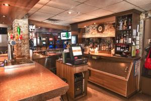 a bar with a counter and a bar with alcohol at Hotel Le Plaza in La Baie