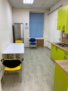 a kitchen with yellow cabinets and a table and chairs at Хостел Мажор in Kharkiv