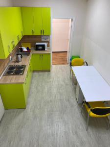 卡爾可夫的住宿－Хостел Мажор，厨房配有绿色橱柜和桌椅