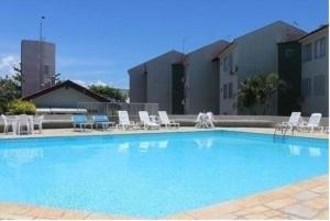 a large swimming pool with lounge chairs and a building at Brejatuba Residence! Conforto e lazer em excelente condomínio in Guaratuba