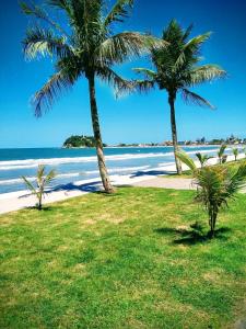 two palm trees on a beach with the ocean at Brejatuba Residence! Conforto e lazer em excelente condomínio in Guaratuba