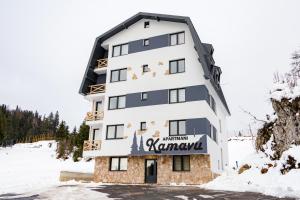 a building with a sign on it in the snow at Apartmani Kamavu in Jahorina