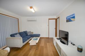 uma sala de estar com um sofá azul e uma televisão em Kiama Coastal Escape em Kiama