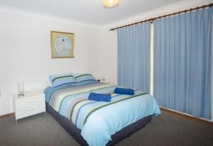 um quarto com uma cama e uma janela com cortinas azuis em Kiama Coastal Escape em Kiama
