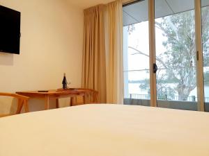 Habitación con cama y ventana con mesa. en Nagambie Waterfront Motel en Nagambie