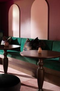 The Central Private Hotel by Naumi Hotels في كوينزتاون: أريكة خضراء مع طاولتين في غرفة