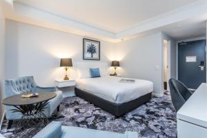 een hotelkamer met een bed, een tafel en stoelen bij Hotel Kingsley in Brisbane