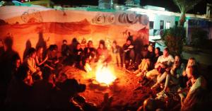 Un groupe de gens assis autour d'un feu dans l'établissement November Camp, à Dahab