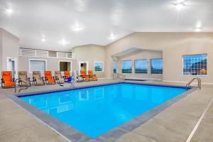 a swimming pool with orange chairs in a building at AmericInn by Wyndham Pella in Pella
