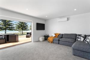 a living room with a couch and a tv at Ohope Beachside Retreat - Ohope Holiday Home in Ohope Beach