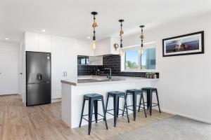 a kitchen with white cabinets and a counter with stools at Ohope Beachside Retreat - Ohope Holiday Home in Ohope Beach