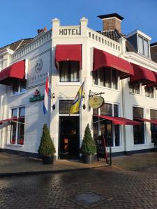 a white building with flags in front of it at Hotel Restaurant 't Heerenlogement in Harlingen