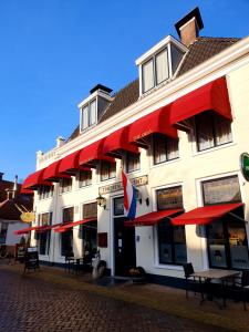 a building with red umbrellas on a street at Hotel Restaurant 't Heerenlogement in Harlingen
