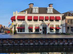 a building with red awnings on the side of a river at Hotel Restaurant 't Heerenlogement in Harlingen