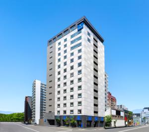 Un edificio alto y blanco en una calle de la ciudad. en HOTEL MYSTAYS Sapporo Station, en Sapporo