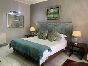 a bedroom with a bed with two tables and two lamps at Rabbit Hole Hotel in Krugersdorp