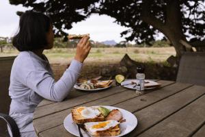 a woman sitting at a table with a plate of food at Grampians Historic Tobacco Kiln in Moutajup