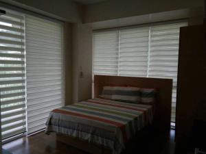 a bedroom with a bed with blinds on the windows at Creys Condo 2 at Pico de Loro Cove in Nasugbu