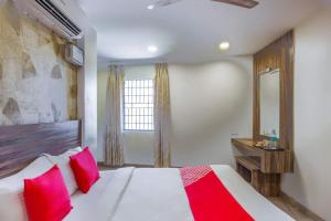 een slaapkamer met een bed met rode kussens en een raam bij Serenity Inn in Chennai