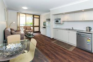 cocina y sala de estar con mesa de cristal en Silver Sands Resort Mandurah, en Mandurah