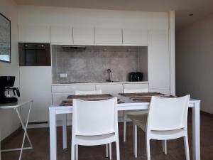 une cuisine avec des chaises blanches et une table blanche dans l'établissement appartement seafront, à Ostende