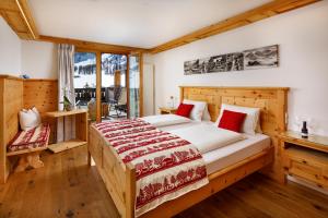 a bedroom with a large bed with red pillows at Walserhuus Sertig in Sertig Döfli +69 photos