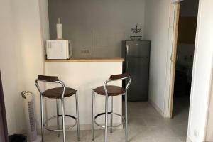 uma cozinha com 2 bancos de bar e um frigorífico em Studio sympathique proche de la gare et l’hopital em Montereau-faut-Yonne