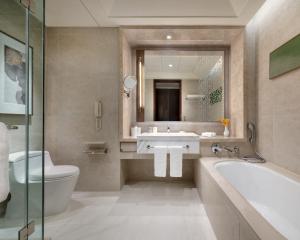 a bathroom with a sink and a tub and a toilet at Shangri-La Tangshan in Tangshan