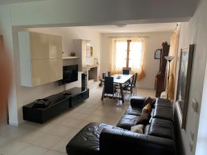 a living room with a black leather couch and a table at Podere Venanzio in Lido di Camaiore