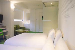 um quarto com uma cama branca e uma cadeira em Time Flyer Hotel em Taichung