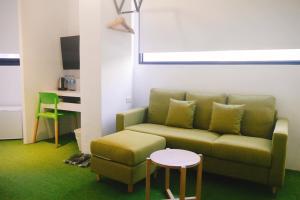 a living room with a green couch and a stool at Time Flyer Hotel in Taichung