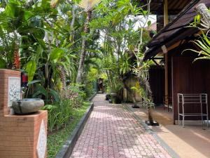 a brick path in a garden with trees and plants at De Puspa Residence Seminyak in Seminyak