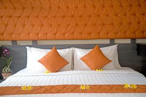 a bed with orange and white pillows in a room at Indi Villas - The Ambika in Seminyak