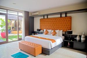 a bedroom with a large bed with an orange headboard at Indi Villas - The Ambika in Seminyak