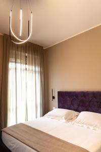 sypialnia z łóżkiem z fioletowym zagłówkiem i oknem w obiekcie Bob W Ticinese w Mediolanie