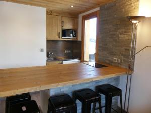 una cocina con encimera de madera con taburetes. en Comfortable flat close to the slopes and shops, en Les Allues