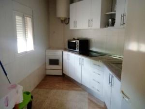 a kitchen with white cabinets and a microwave at 2 bedrooms house with shared pool and enclosed garden at Cartagena in Cartagena