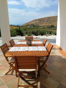 una mesa de madera con sillas y vistas a la montaña en One bedroom apartement with sea view and furnished garden at Montallegro 2 km away from the beach, en Montallegro