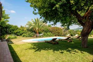 a swimming pool with two chairs and a tree at Bright apartment in Castelbellino - 75 m² - Shared Pool in Castelbellino