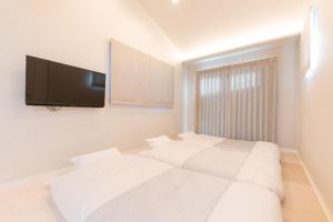 The Guest Villa 箱根湯本 V-I في هاكوني: غرفة نوم بسريرين وتلفزيون بشاشة مسطحة