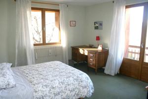 1 dormitorio con cama, escritorio y ventana en Chalet de 7 chambres avec sauna jardin et wifi a Briancon a 1 km des pistes, en Briançon