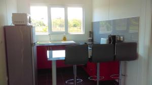 a kitchen with a counter with chairs and a refrigerator at Maison charmante à Macouria avec jardin et climatisation. in Guenouillet
