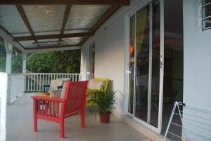 a porch with a red rocking chair and a window at Studio avec vue sur la mer terrasse amenagee et wifi a Fort de France a 8 km de la plage in Fort-de-France