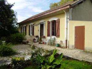 a yellow house with a red door and a patio at Maison accueillante à Gabarret, jacuzzi et jardin in Gabarret