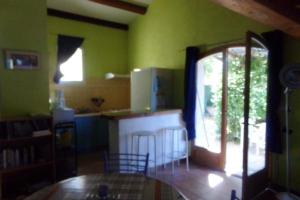 a kitchen with green walls and a table and chairs at Appartement d'une chambre avec piscine partagee jardin clos et wifi a Le Luc in Le Luc