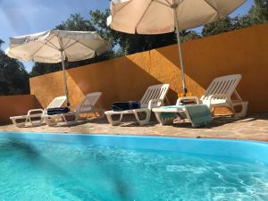 un grupo de sillas y sombrillas junto a una piscina en 3 bedrooms villa with private pool and furnished terrace at El Saucejo, en Saucejo