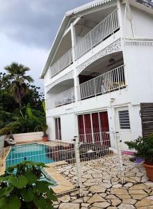 a white house with a swimming pool in front of it at Appartement confortable à Saint-Paul 70 m² avec piscine partagée in Saint-Paul
